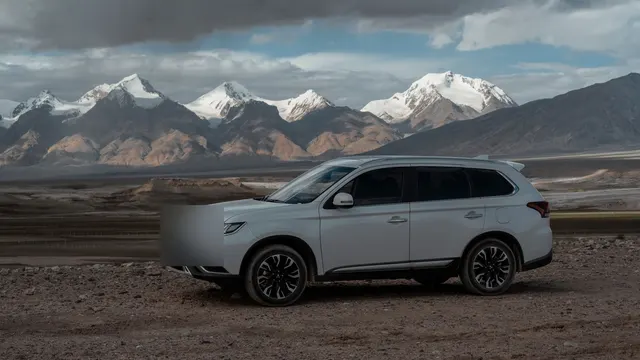 Beyaz SUV, karlı dağların önünde